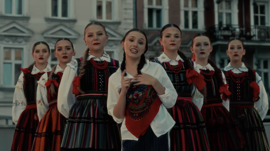 Kadr z teledysku Diiya w serwisie Youtube. Przedstawia wokalistkę w otoczeniu naszych tanecerek w strojach opoczyńskich