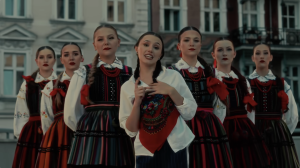 Kadr z teledysku Diiya w serwisie Youtube. Przedstawia wokalistkę w otoczeniu naszych tanecerek w strojach opoczyńskich