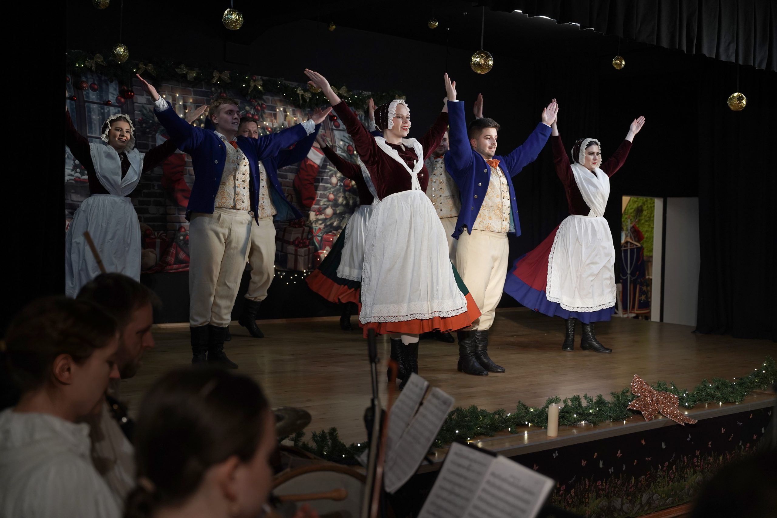 dorośli w strojach dolnośląskich tańczą tańce dolnośląskie na scenie w oprawie świątecznej