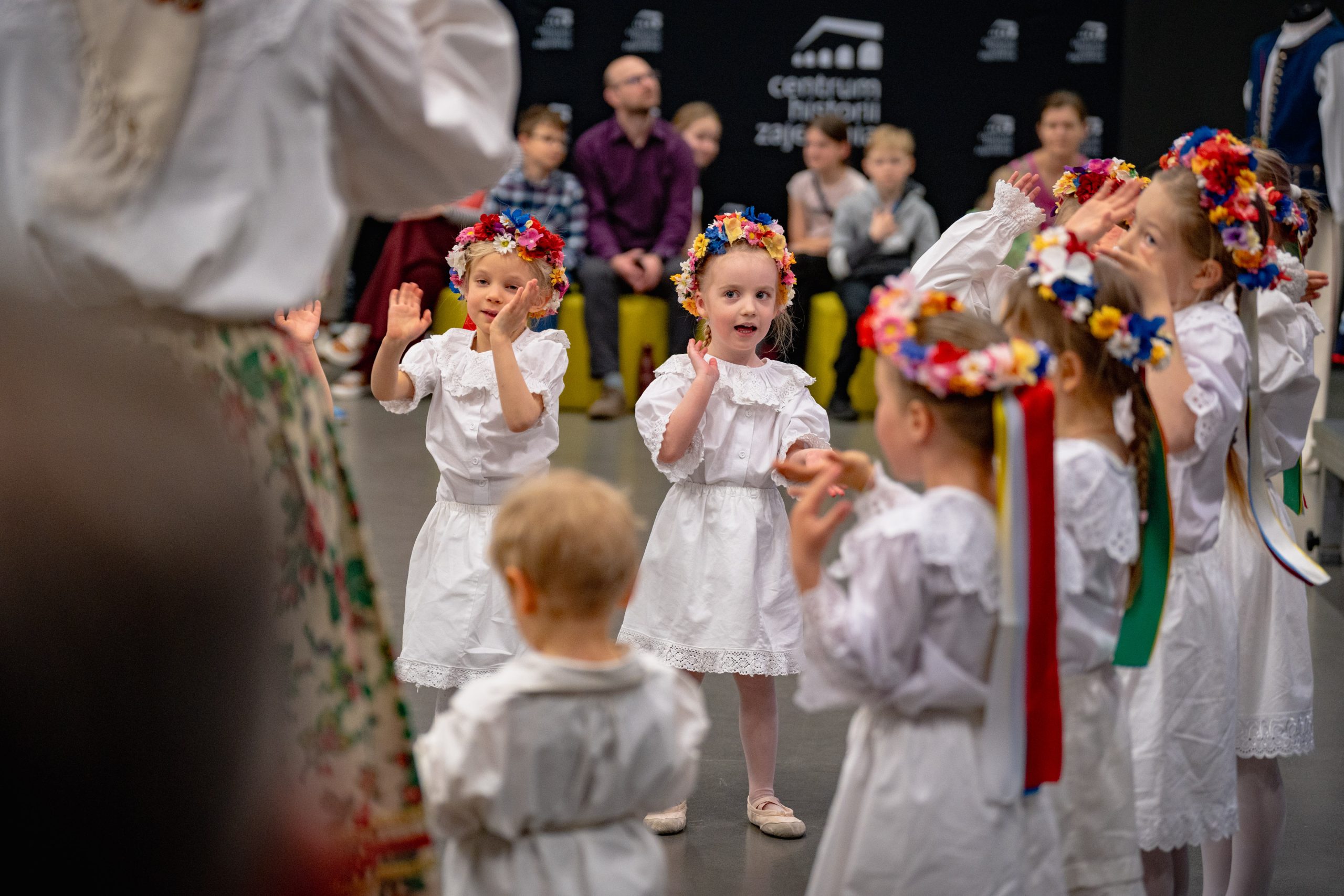 dzieci 3-6 lat w białych strojach stoją w trójce i gestykulują do piosenki grożąc palcem