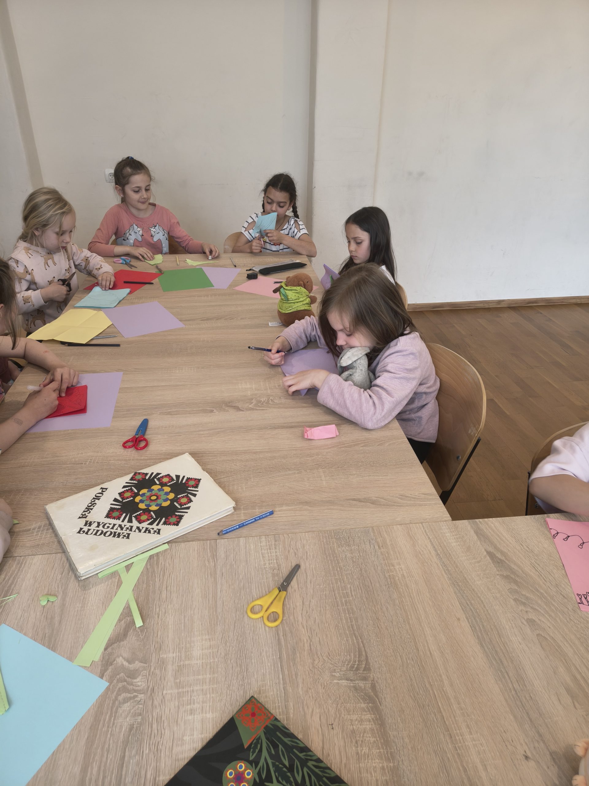 warsztaty wycinanek, dzieci siedzą przy stołach nad swoimi wycinankami